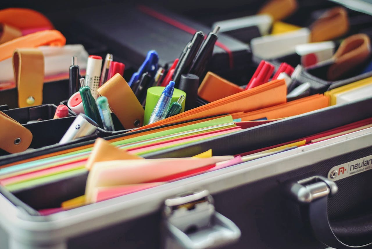 Services A collection of colorful office supplies neatly arranged in a suitcase, perfect for professionals on the go.